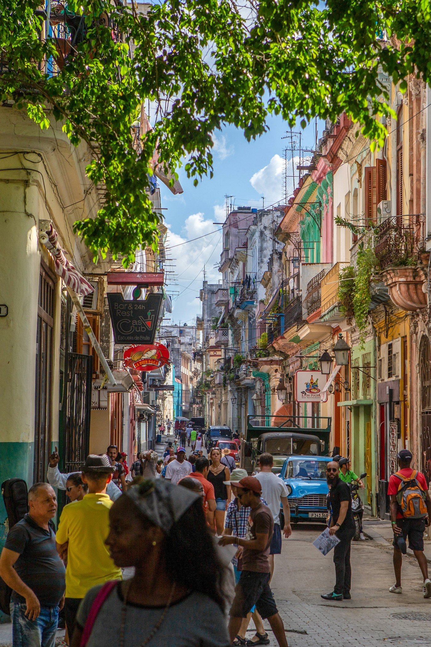 Calle transitada de La Habana con un automóvil azul